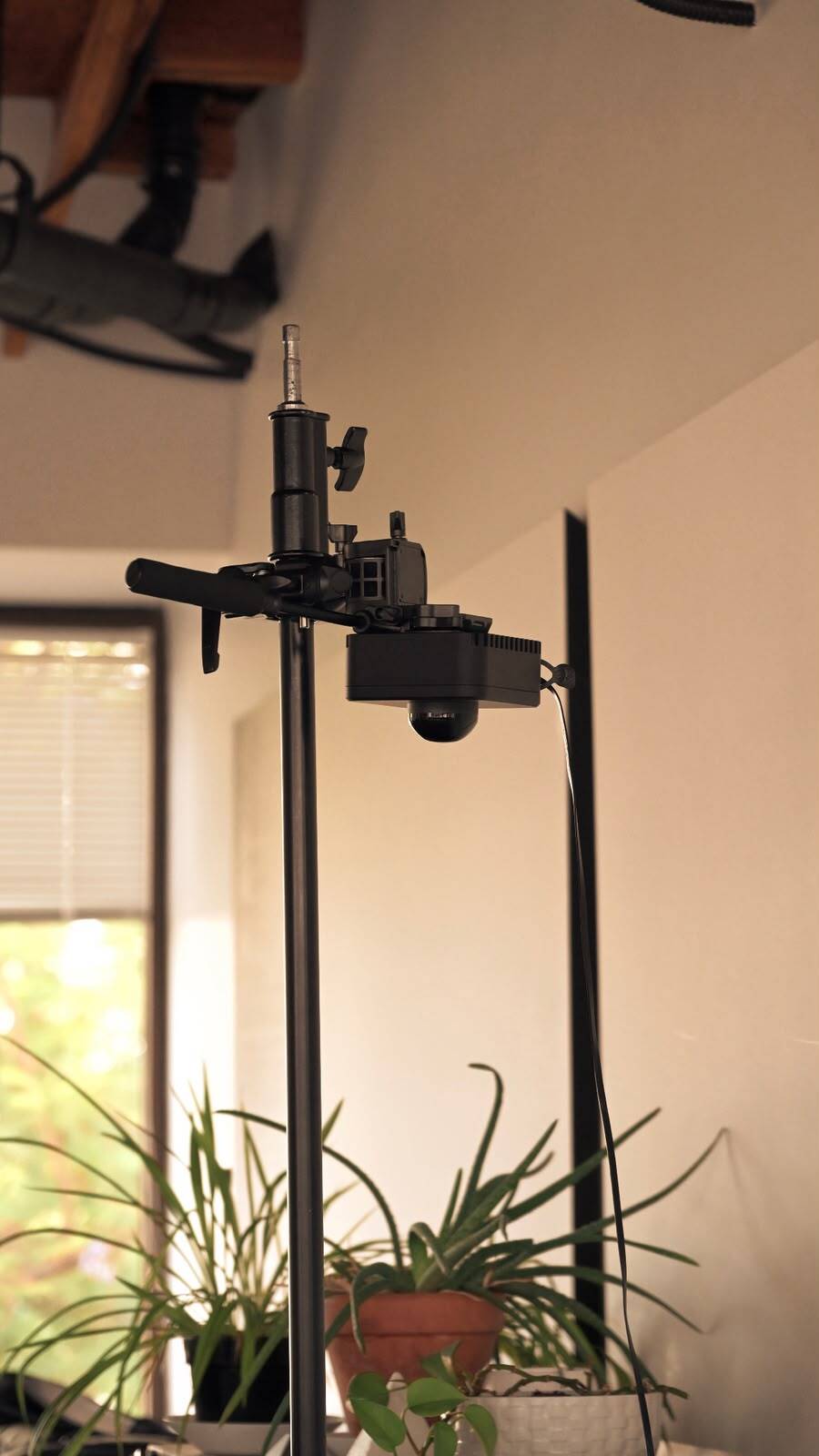 A LiDAR sensor hanging from a clamp on top of a light stand
